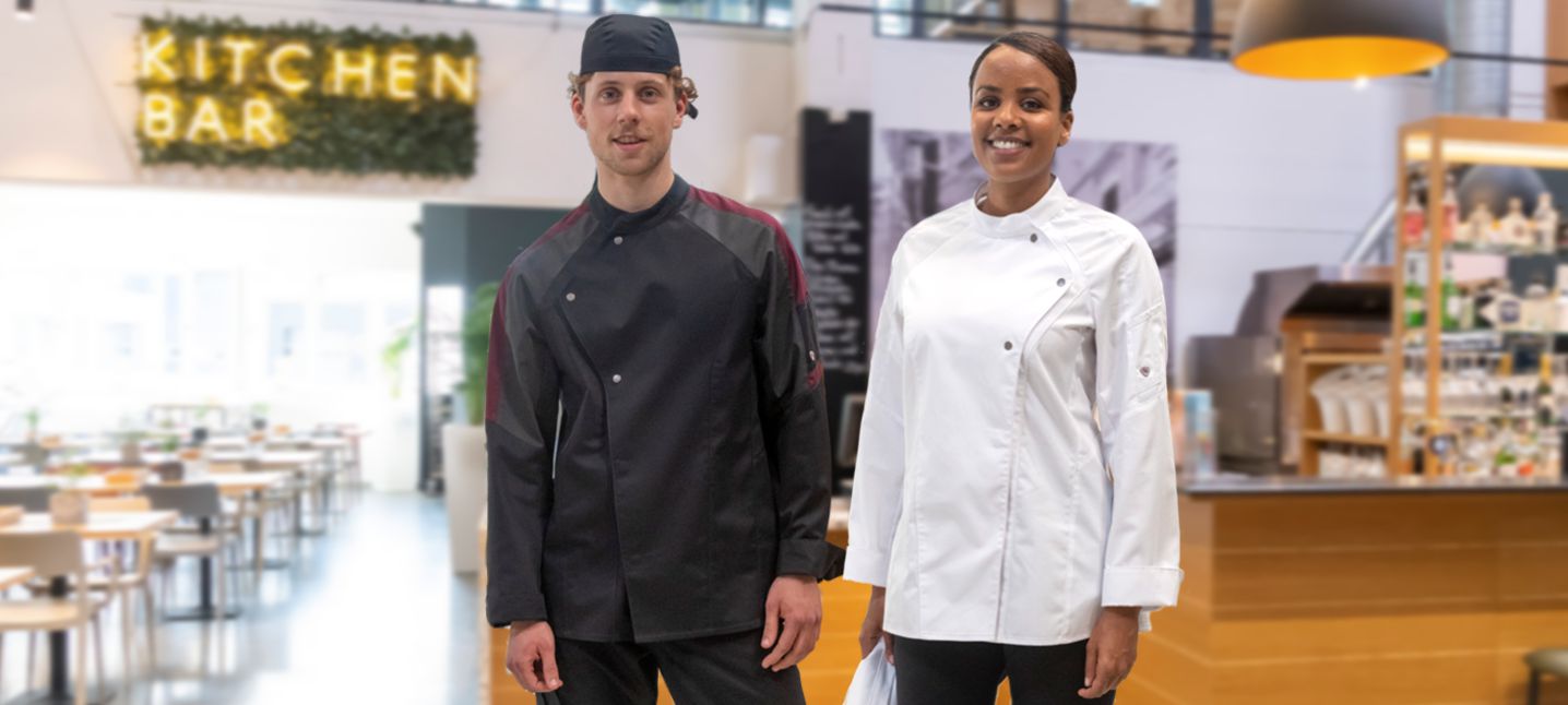 Une femme et un homme portant une veste de cuisine et un bandeau se tiennent dans une cuisine.
